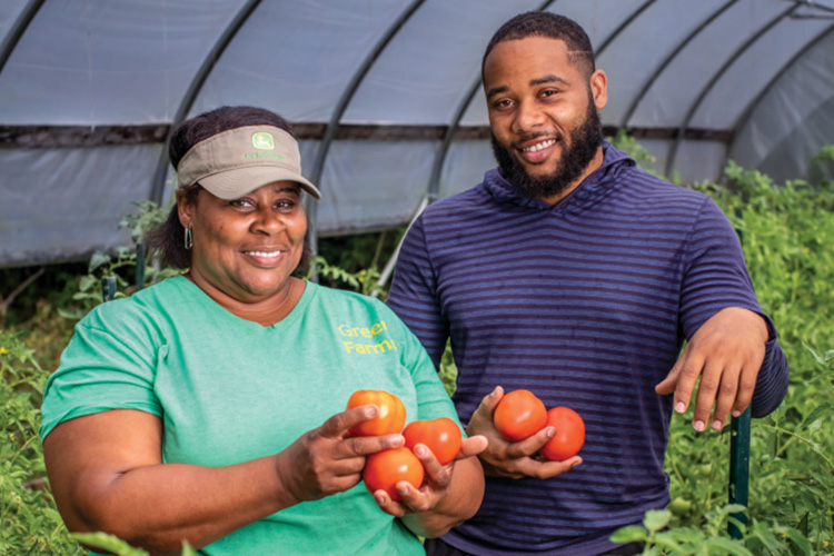 Denise Jamerson and her son DeAnthony Jamerson holding tomatoes in the greenhouse