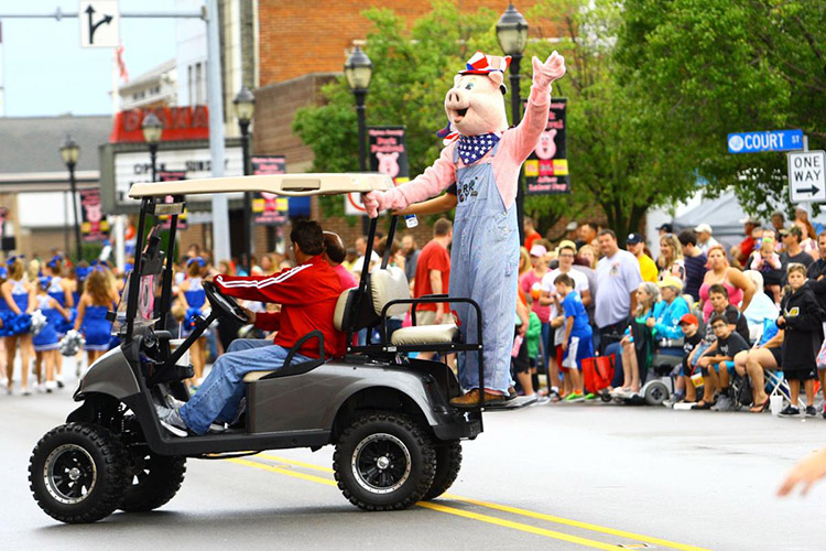 Pork festival pig mascot riding on golf cart; Indiana fall events