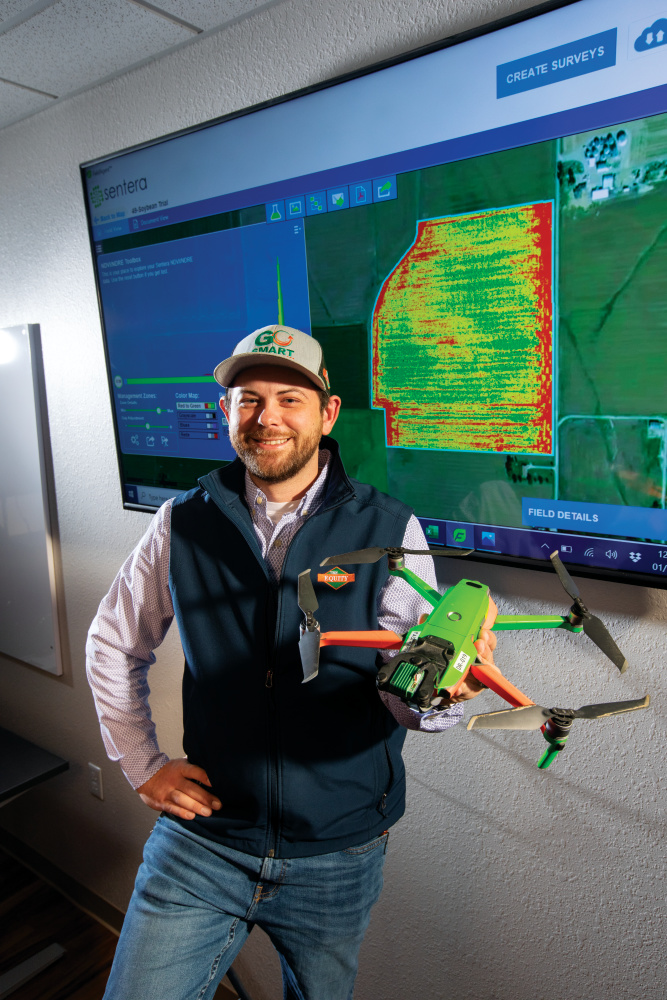 Justin McKain holds a drone while in front of a map showing the crop health of a field