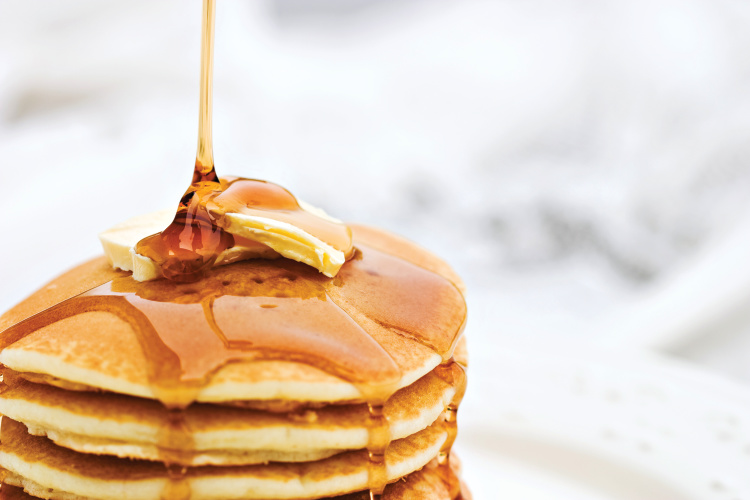 Maple syrup pouring onto pancakes