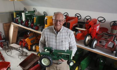 Steve Maple holds one of the toy tractors standing in front of his farm toy collection