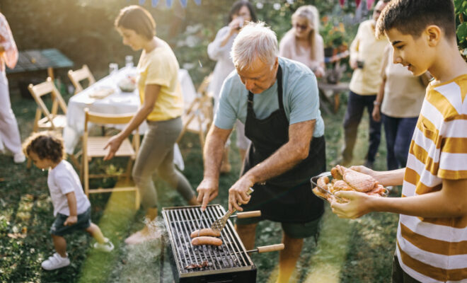 Man grilling hot dogs at a backyard bbq
