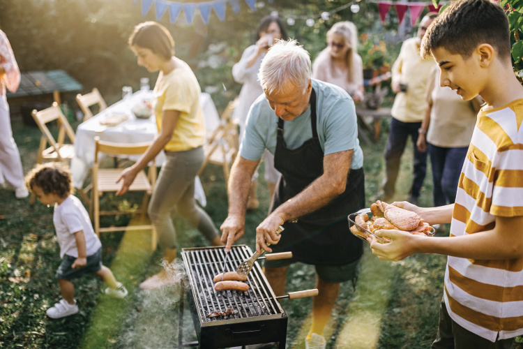 Man grilling hot dogs at a backyard bbq