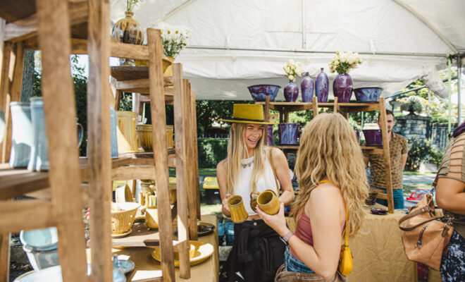 Two women shopping at a pottery booth at the Madison Chautauqua Festival of Art