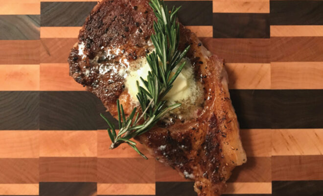 Cooked steak with butter and herbs on top of it