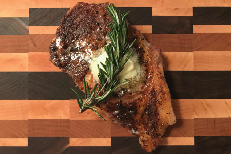 Cooked steak with butter and herbs on top of it