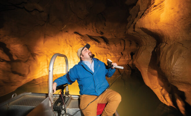 Nic Kaufman in a boat on the underground river