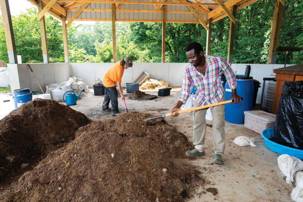Aidan Coon and Don Masumbuko mixing compost