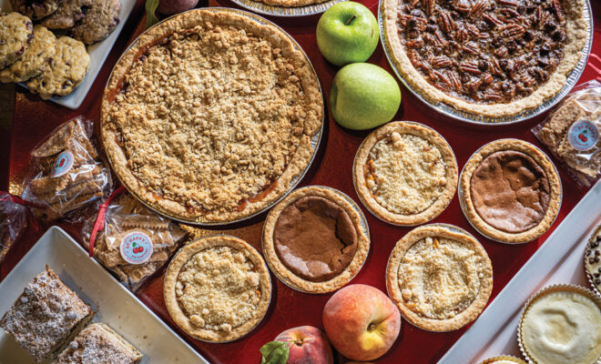 Be Happy Pie Company large and small pies sitting among apples and peaches