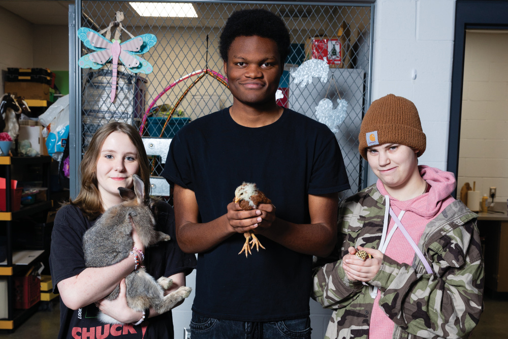 Kaya Blankenship, Jayse Evans and Alex Payne holding chickens and rabbits at the school