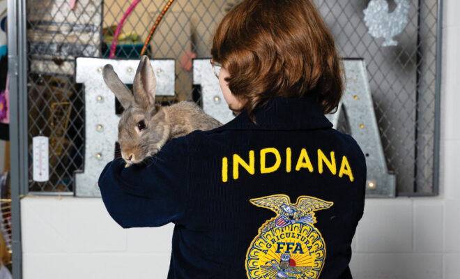 Ayden Huston holding a rabbit wearing her FFA jacket