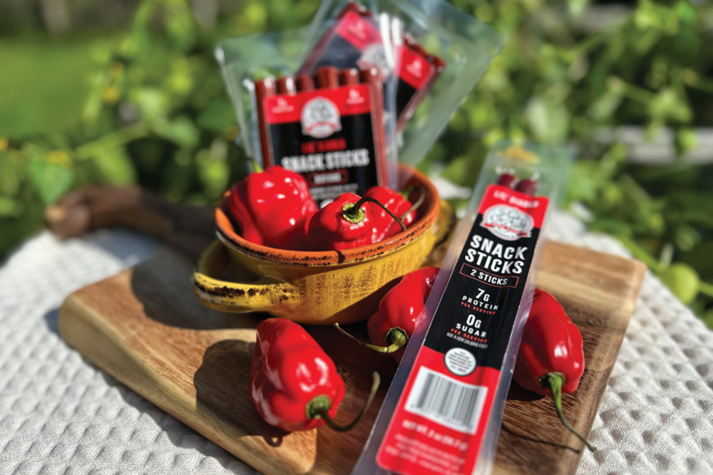 Pig's Tale Snack Sticks packs in a basket with peppers