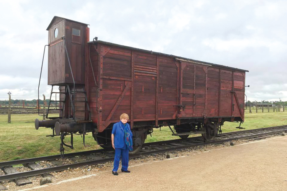 Eva Mozes Kor stands beside a boxcar at Auschwitz