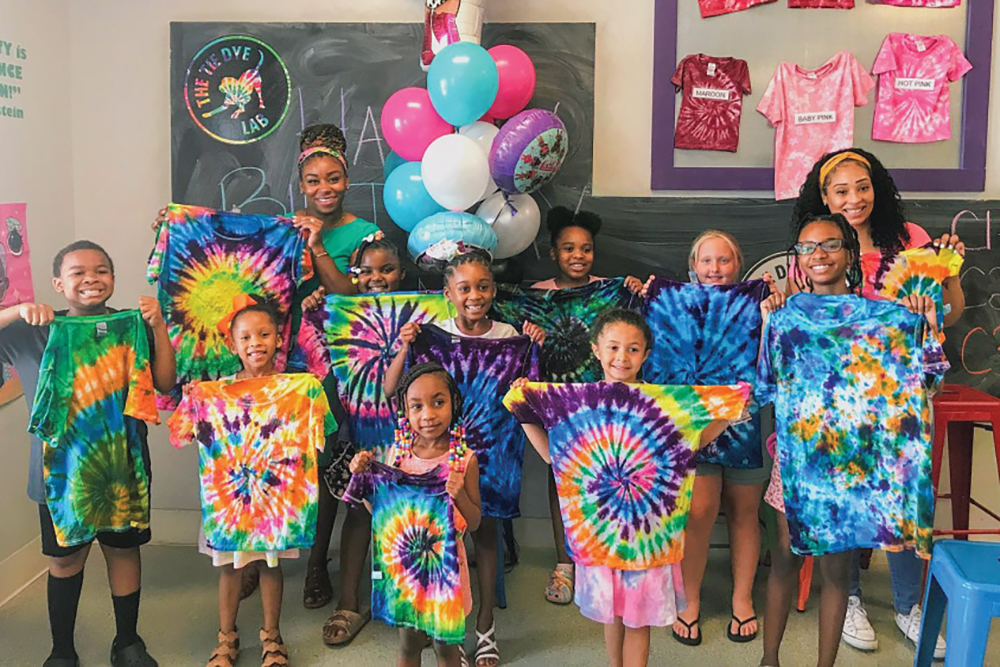 A group poses with their tie-dye shirts made at The Tie Dye Lab