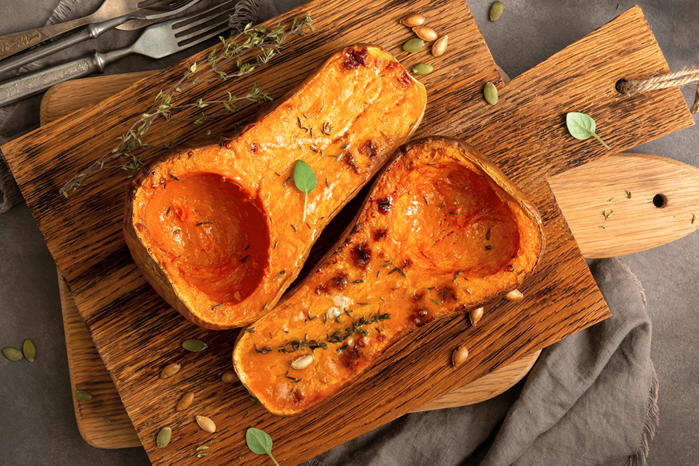 Baked butternut squash cut in half with herbs on it