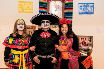 Two women and a man pose for a photo in Day of the Dead