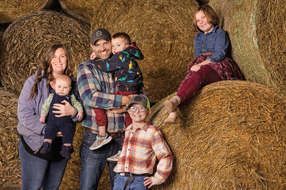 The Beneker family posing for photos on round hay bales at Beneker Family Farms
