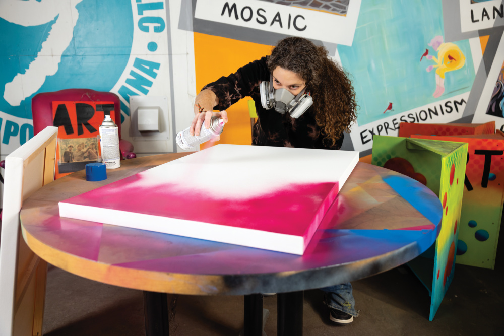 Joy Hernandez spray painting a new canvas
