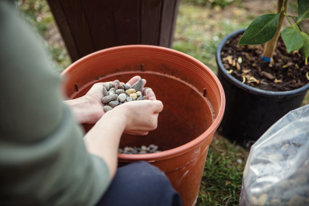 Up-close of someone about to put rocks in the bottom of a flower pot