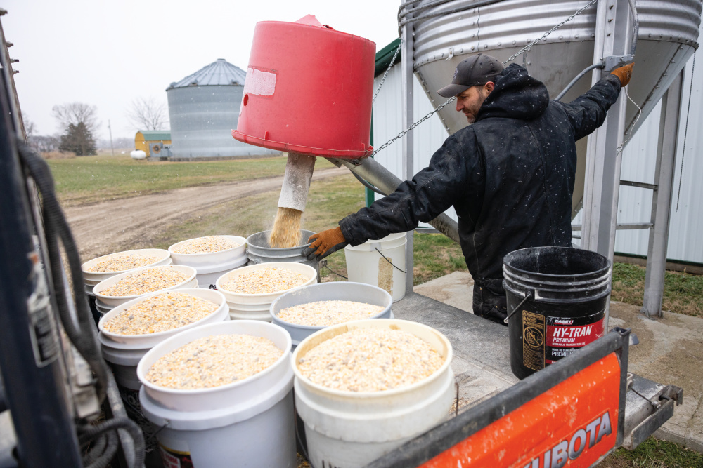 Allen Beneker fills up buckets with feed for the cattle at Beneker Family Farms 