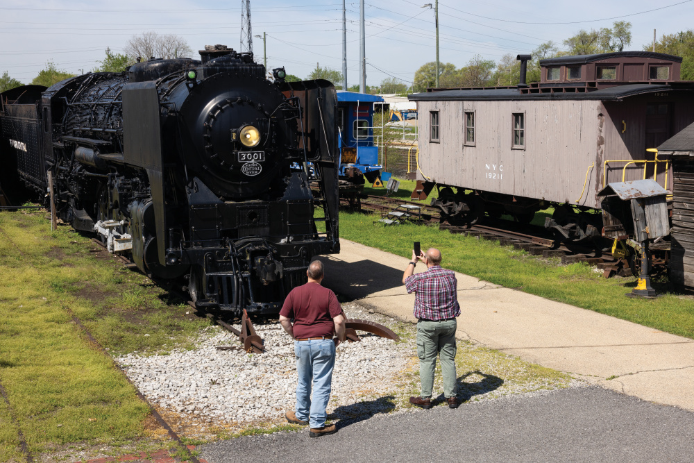Two men taking a photo of a train engine at the National New York Central Railroad Museum