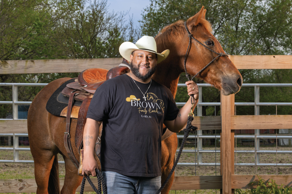 Chris Brown posing for a photo next to one of his horses at Brown Family Ranch