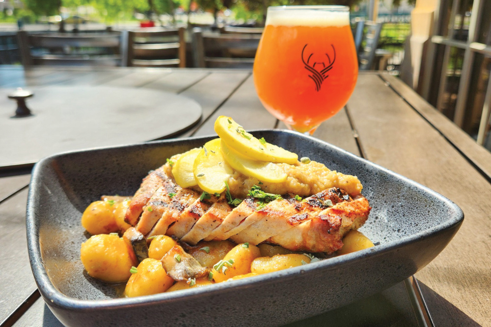 Food dish and beer sitting on a table at Brass Elk Brewing