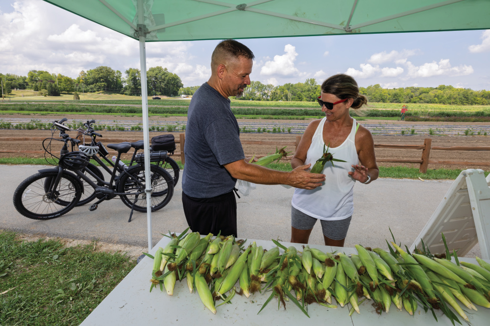 A couple picks up sweet corn from Fishers AgriPark
