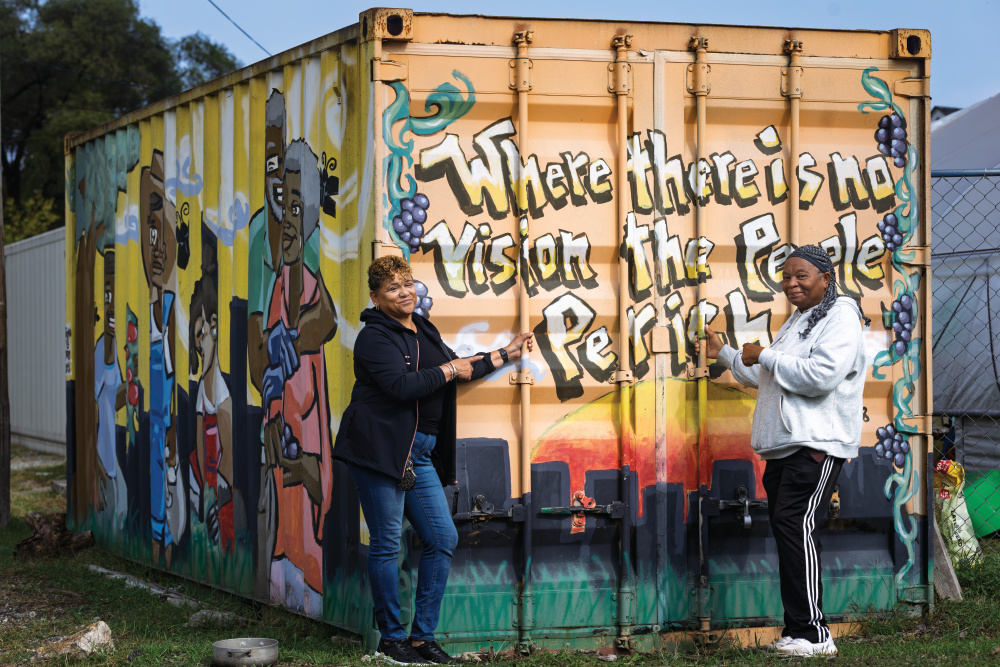 Frieda Graves and Dorothy Fine pose in front of a painted storage container at Faith CDC