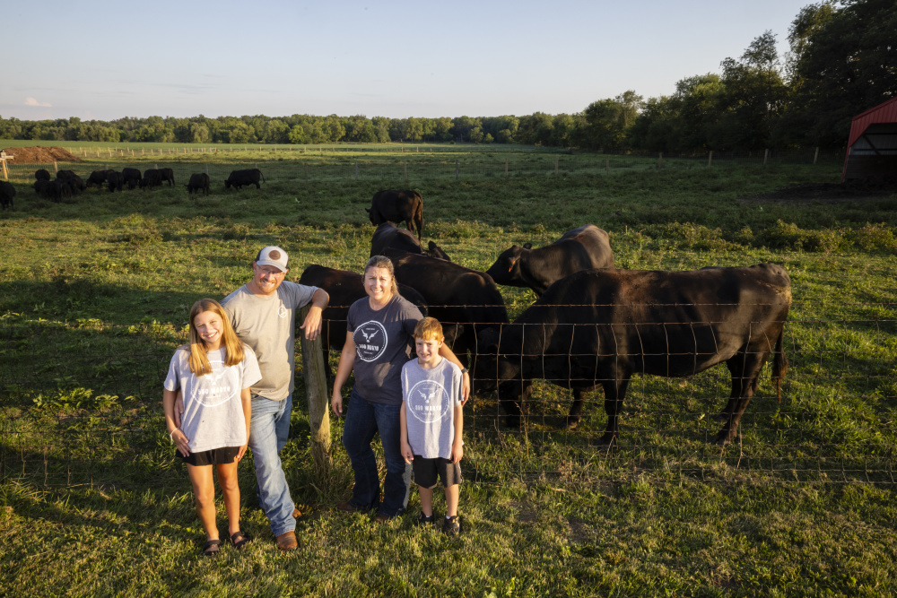 Adam and Elizabeth Stonecipher with their children, Hadley and Easton on their farm with Angus and Wagyu cattle in the background